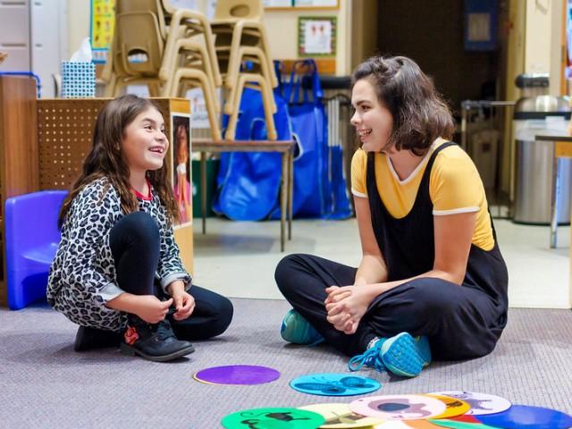 teaching assistant sitting on floor with child and a game